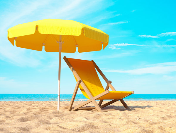 Ein Strand mit gelber Sonnenliege und gelben Sonnenschirm.