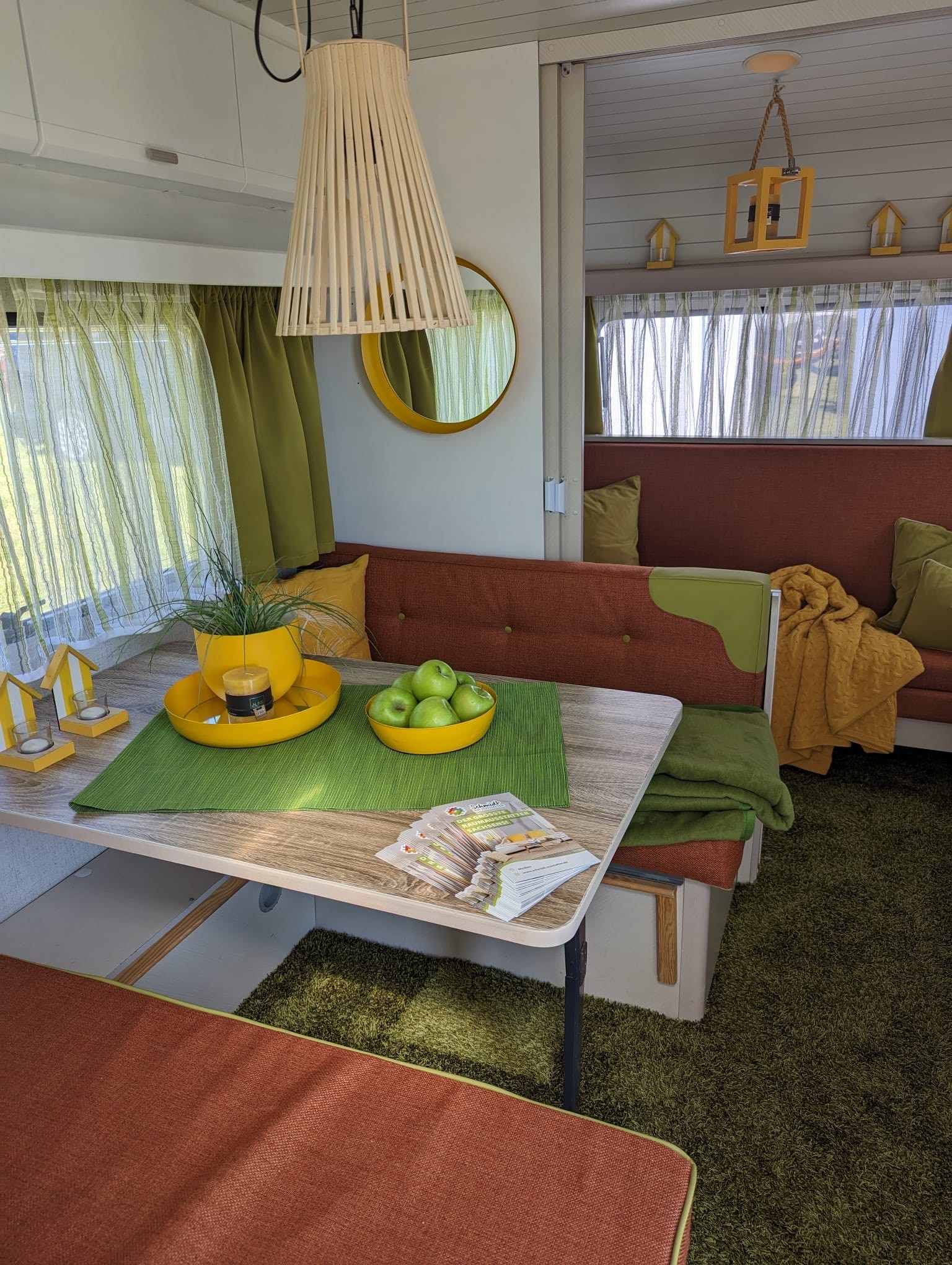 Inneneinrichtung eines Campers mit einer Rückbank, sowie zwei Sitzbänken an einem Tisch.