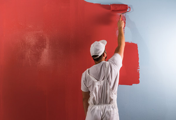 Ein Mann, der die Wand rot streicht.