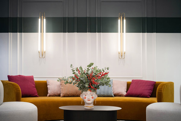 Großes, dunkelgelbes Sofa, Wand im Hintergrund ziervoll mit Zierleisten aufgehübscht.