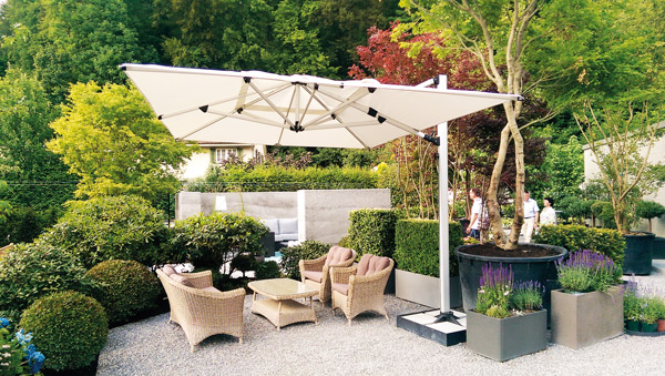 Außenbereich in einem Garten mit Stühlen und einem modernen, weißen Sonnenschirm.